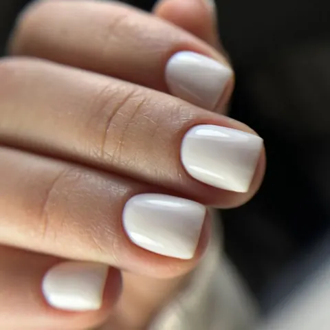 Manicura semipermanente en blanco lechoso sobre uñas cortas