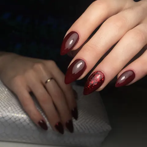 Uñas en burdeos con un detalle de purpurina